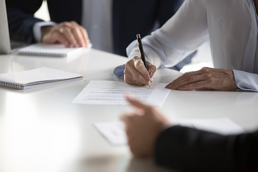 Close Up Female Hands Affirming Contract With Signature During Meeting