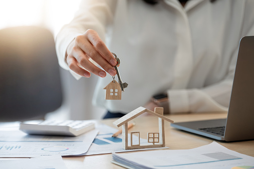 Female Hand Holding House Key, Real Estate Agent Woman Working House Loan At Her Office